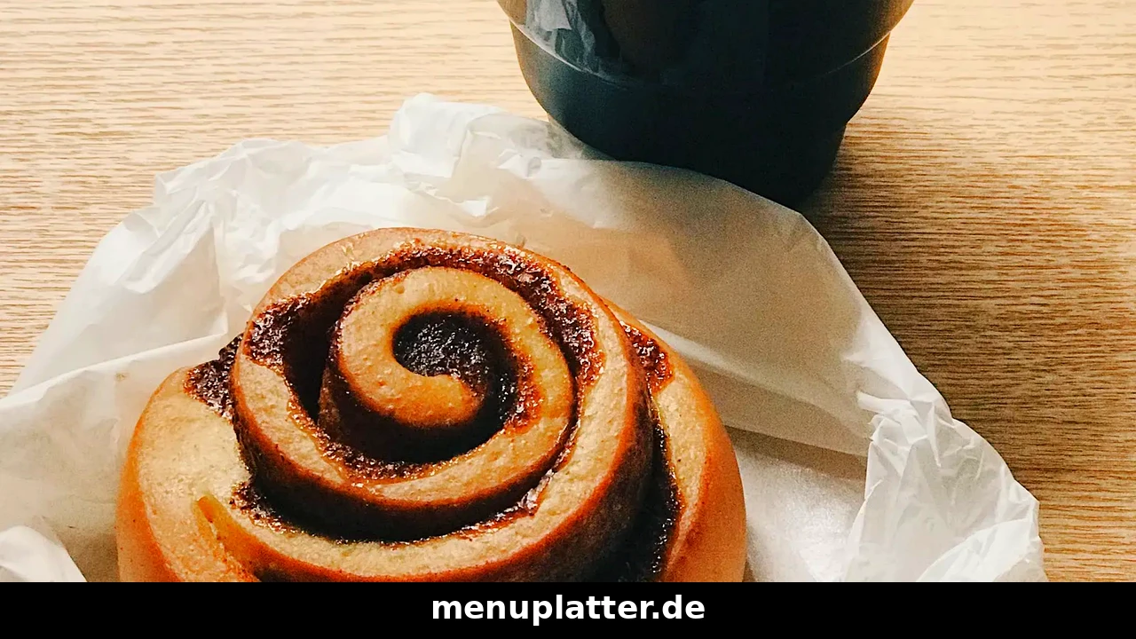 Espresso House Preise Deutschland mit Zimtschnecke auf Papier und einer Tasse Kaffee auf hellem Holztablett